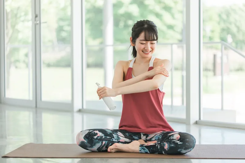 運動後にオイルを腕になじませる女性